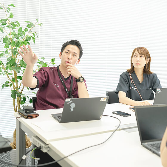 モニターを見ながら会話する男女社員